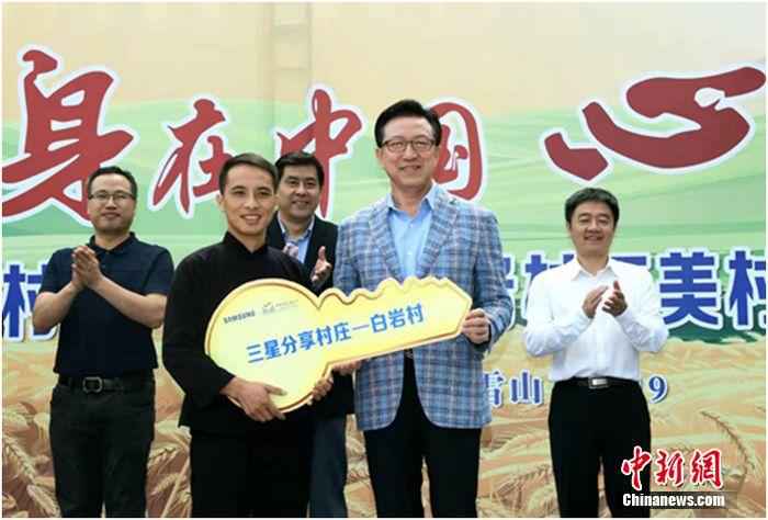 唐文德(前左)从中国三星总裁黄得圭(前右)手中接过象征希望的金钥匙。 “分享村庄”带火民宿旅游 梯田村走上脱贫振兴路